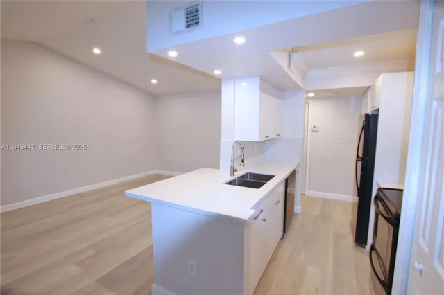 a kitchen that has a sink a refrigerator and a stove top oven