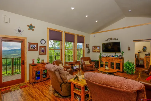 a living room with furniture a flat screen tv and a floor to ceiling window
