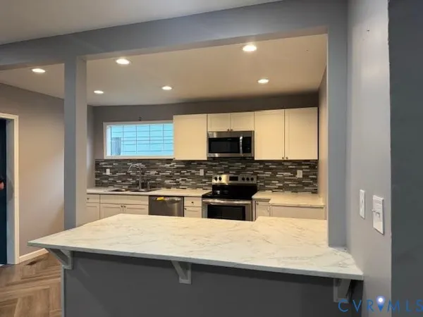 a kitchen with a sink a stove top oven and white cabinets