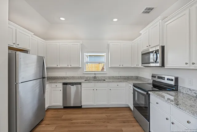 a kitchen with granite countertop a refrigerator stove top oven and sink