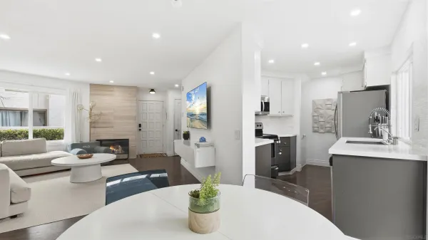 a living room with furniture kitchen area and a refrigerator