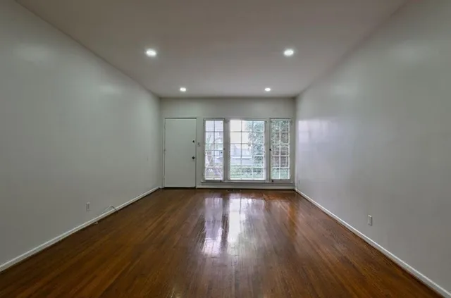 a view of an empty room with wooden floor and a window