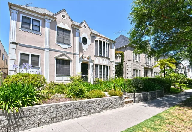 a front view of a multi story residential apartment building with yard and bench