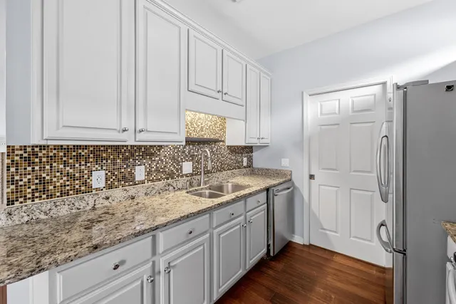 a kitchen with stainless steel appliances granite countertop a refrigerator a sink a stove and oven