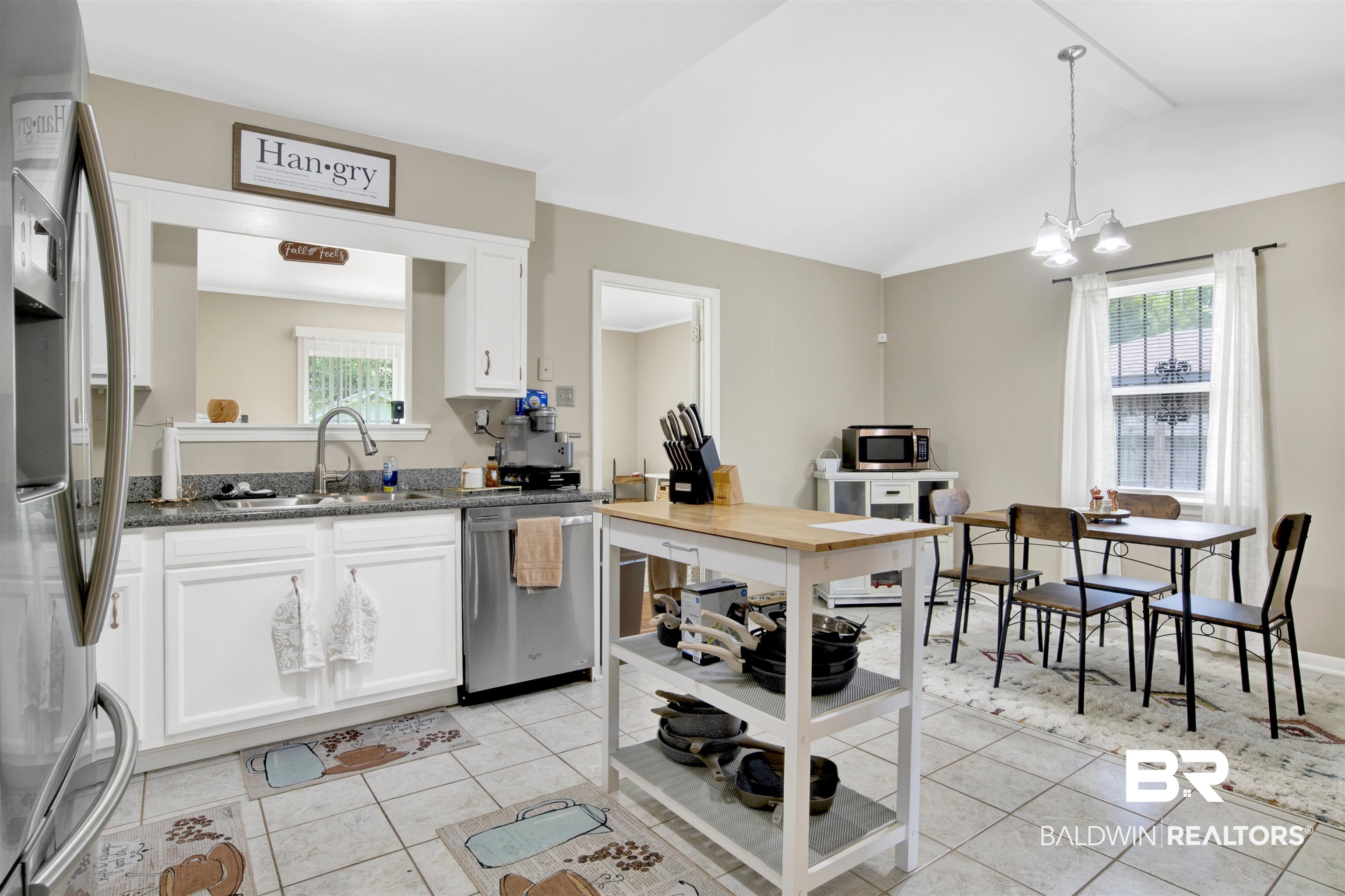 1476 Boudousquie Street Mobile, AL 36605 - Photo 11 of 34 Kitchen with stainless steel appliances, light tile patterned floors, white cabinetry, vaulted ceiling, and dark stone countertops
