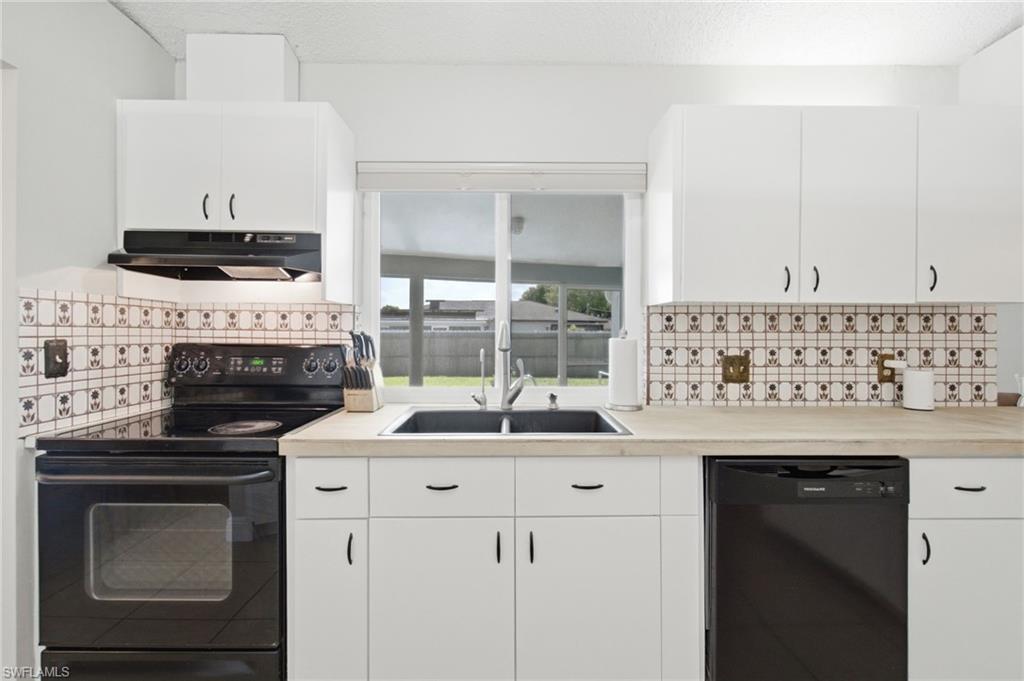 3022 47th Street Southwest Naples, FL 34116 - Photo 15 of 46 Kitchen featuring white cabinetry, black appliances, a black double-basin sink, and light wood-finish countertops
