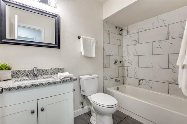 a bathroom with a granite countertop toilet sink and mirror