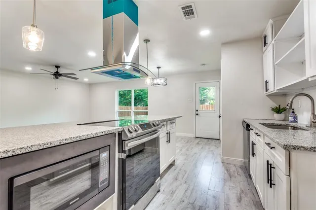 a kitchen with granite countertop a sink stainless steel appliances and cabinets
