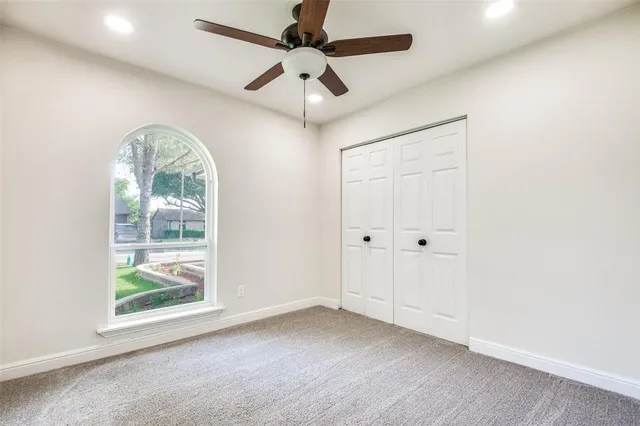 a view of empty room with windows and ceiling fan