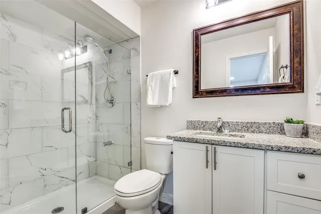 a bathroom with a granite countertop sink mirror and toilet