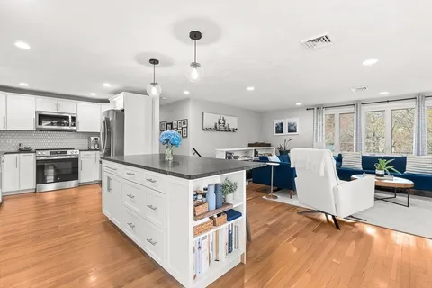 a large kitchen with a large counter top space a sink stainless steel appliances and cabinets