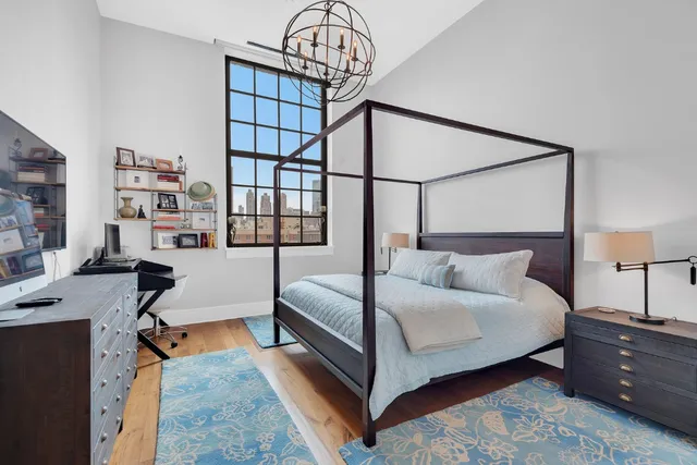 a bedroom with a bed window and a chandelier