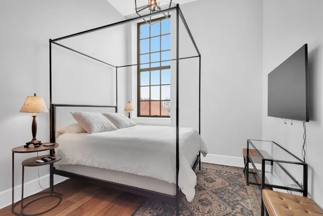 a bedroom with a bed window and a flat screen tv