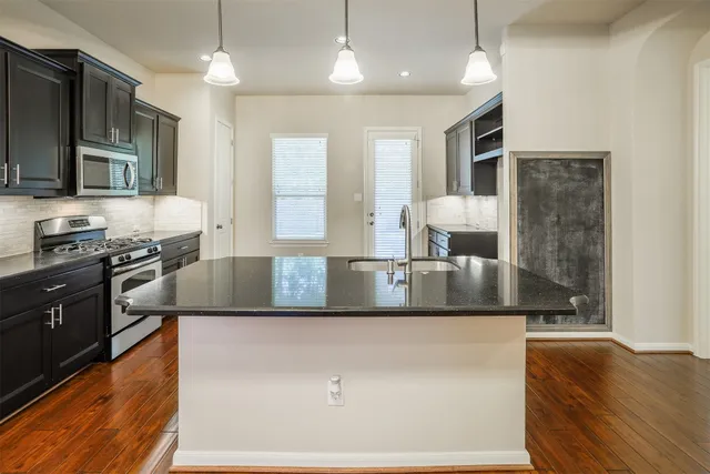 a kitchen with stainless steel appliances granite countertop a sink a stove and a refrigerator