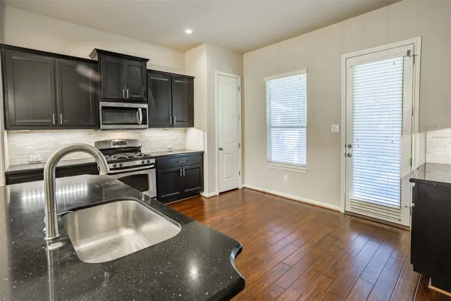 a kitchen with stainless steel appliances granite countertop a stove a sink and a microwave