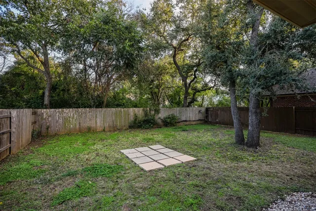 a view of a backyard with large trees and wooden fence