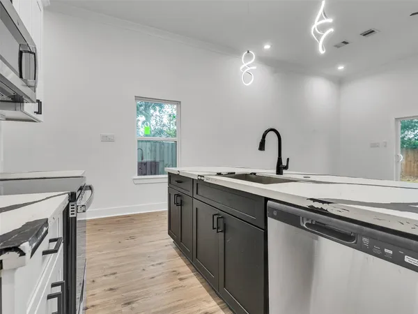 a kitchen with granite countertop a sink cabinets and wooden floor
