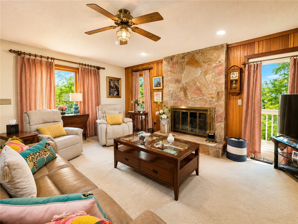 222 Terrace Drive Anderson, SC 29621 - Photo 6 of 37 A spacious living area featuring a majestic stone fireplace, wood paneling, and ample natural illumination.