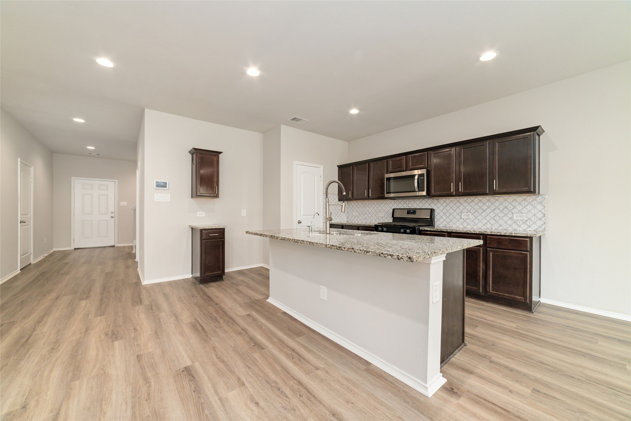 23702 Harrow Field Ln Spring Spring, TX 77373 - Photo 12 of 32 a large kitchen with stainless steel appliances granite countertop a stove a sink dishwasher and a microwave with wooden floor