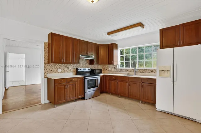 a kitchen with stainless steel appliances granite countertop a refrigerator stove top oven and sink