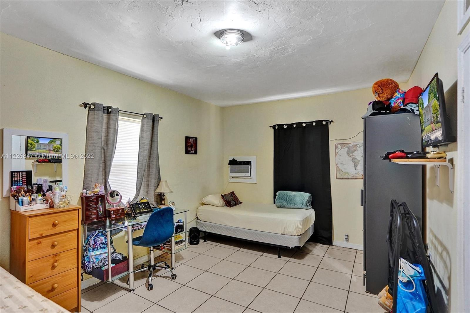 1554 Northwest 58th Street Miami, FL 33142 - Photo 31 of 57 a bedroom with furniture a flat screen tv and a large window