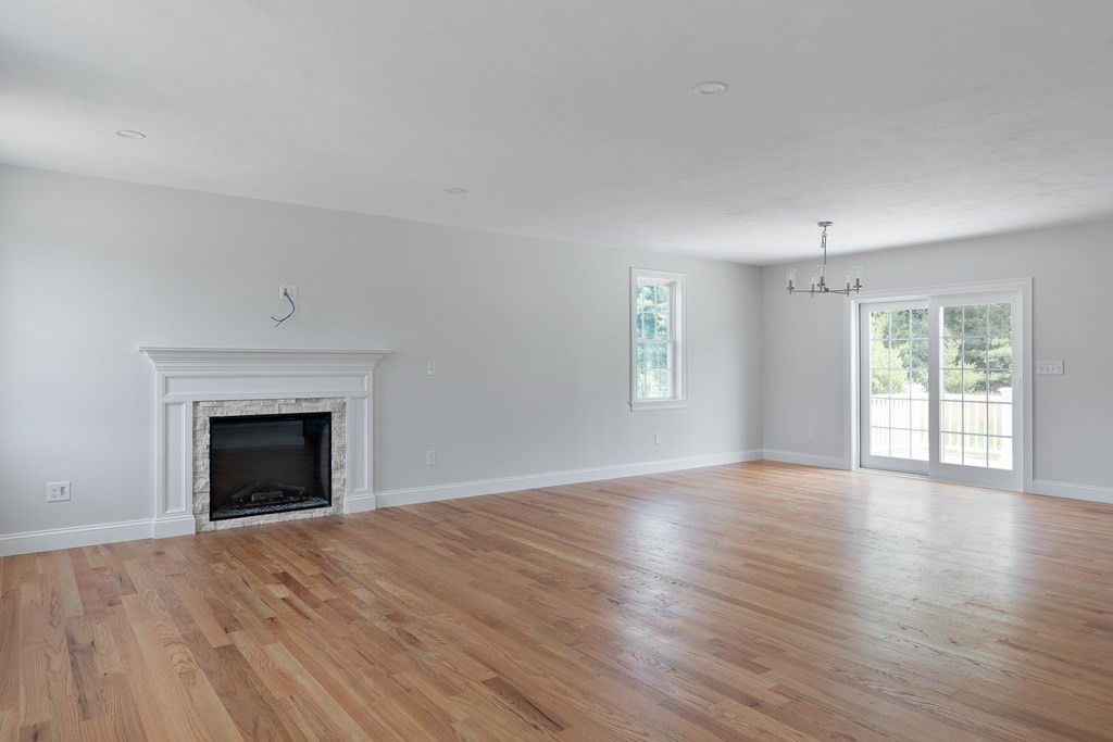 5 May Road Millis, MA 02054 - Photo 4 of 10 an empty room with wooden floor fireplace and windows