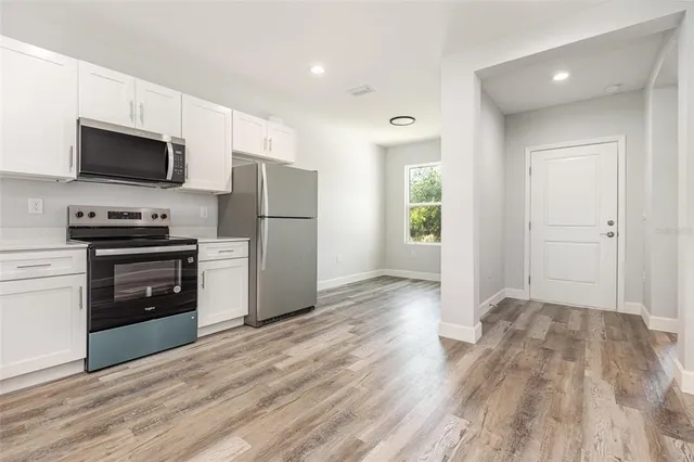 a kitchen with a refrigerator stove and wooden floor