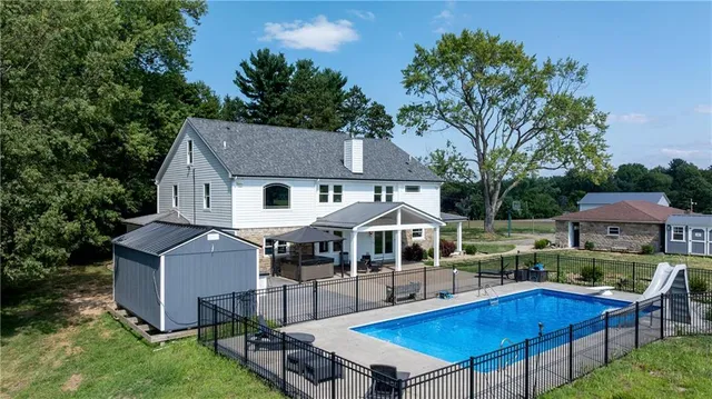 an aerial view of a house with swimming pool next to a yard