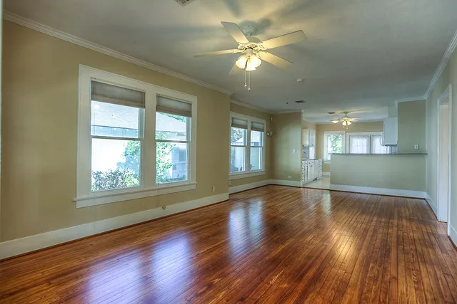 a view of an empty room with wooden floor and a window