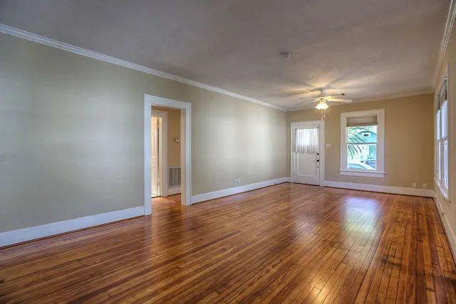a view of an empty room with wooden floor and a window