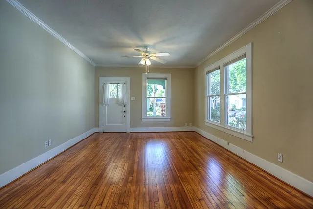 a view of an empty room with wooden floor and a window