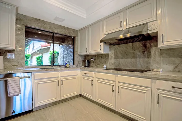 a kitchen with white cabinets and a window