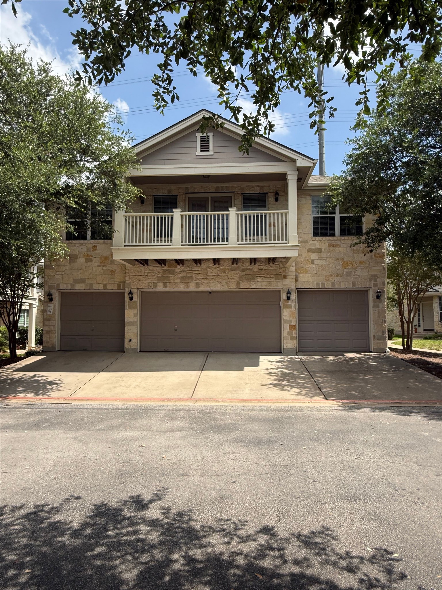 Three attached garages offer ample parking beneath a charming second-story balcony.
