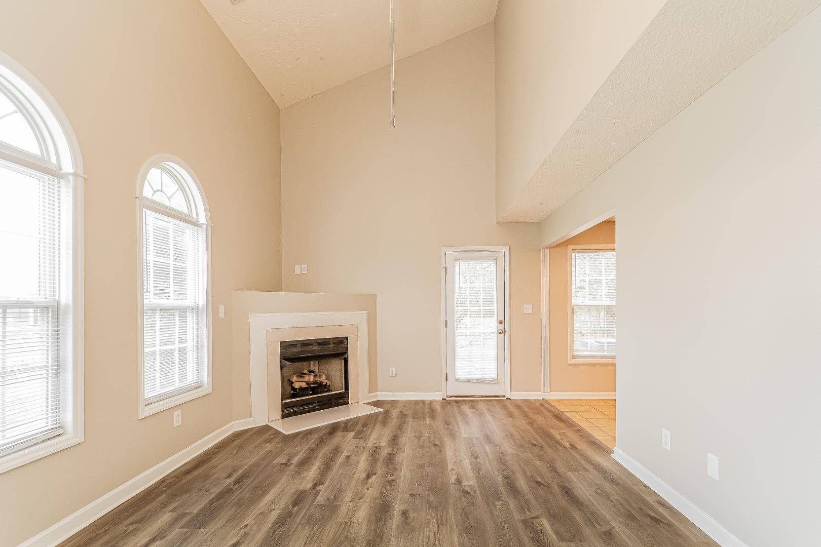 2100 McKinnon Drive Clayton, NC 27520 - Photo 6 of 17 an empty room with windows fireplace and wooden floor