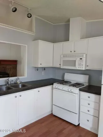 a kitchen with granite countertop a sink cabinets and stainless steel appliances