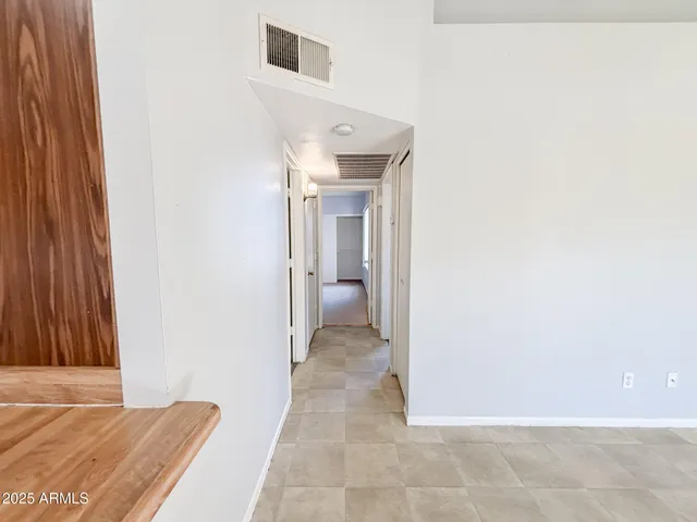 a view of a hallway with wooden floor and a bathroom