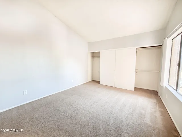 an empty room with windows and refrigerator