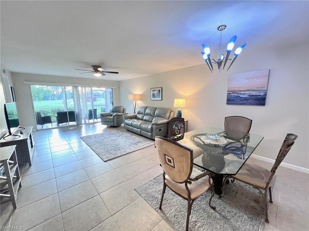 1051 Eastham Way, Unit B104 Naples, FL 34104 - Photo 11 of 23 a living room with furniture a chandelier and a dining table