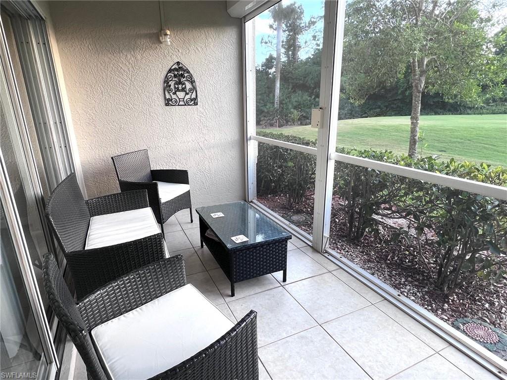 1051 Eastham Way, Unit B104 Naples, FL 34104 - Photo 13 of 23 a living room with a couch and a floor to ceiling window