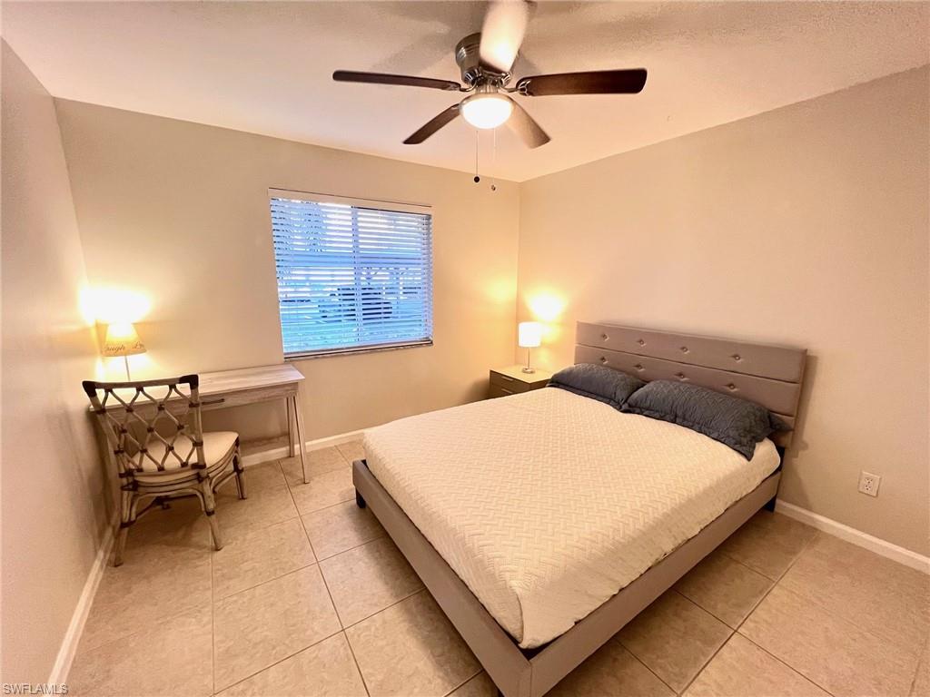 1051 Eastham Way, Unit B104 Naples, FL 34104 - Photo 14 of 23 a bed sitting in a bedroom next to a window