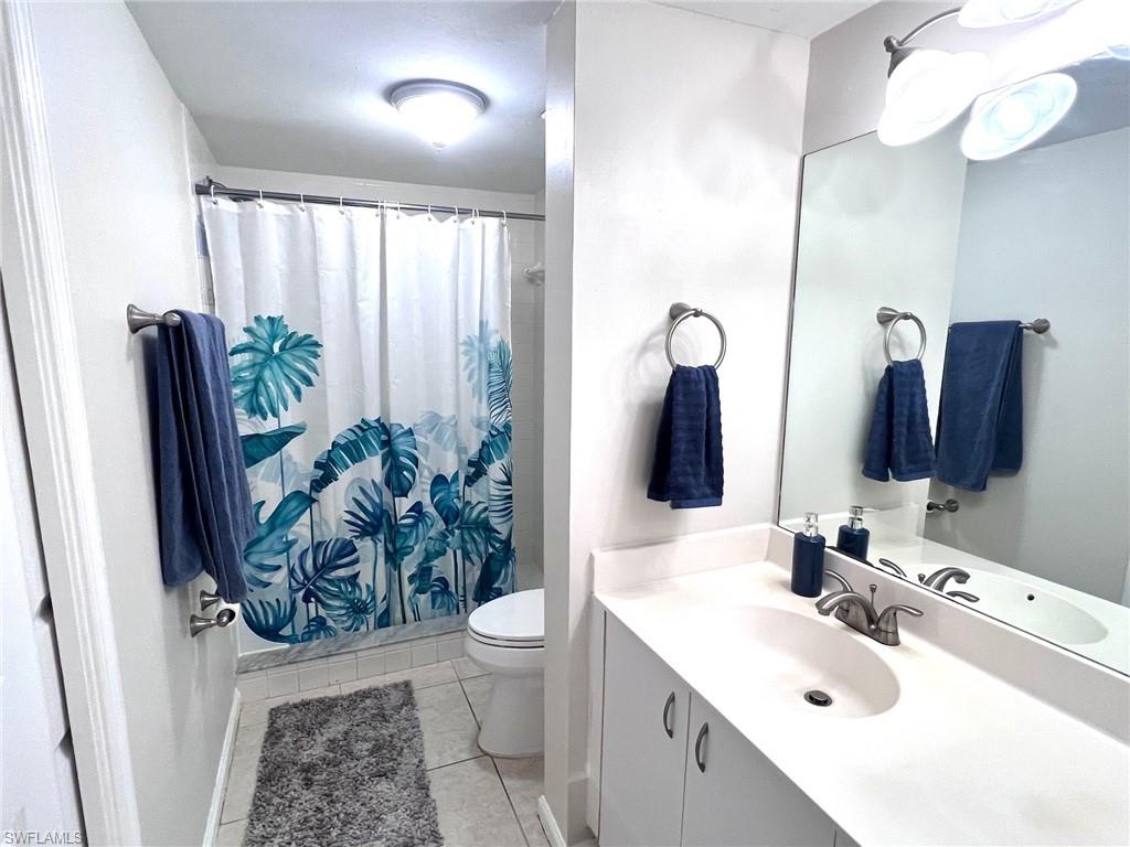 1051 Eastham Way, Unit B104 Naples, FL 34104 - Photo 17 of 23 a bathroom with a sink a toilet and mirror