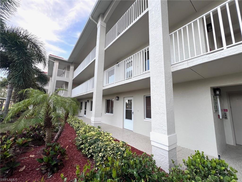 1051 Eastham Way, Unit B104 Naples, FL 34104 - Photo 5 of 23 a front view of a white building with plants