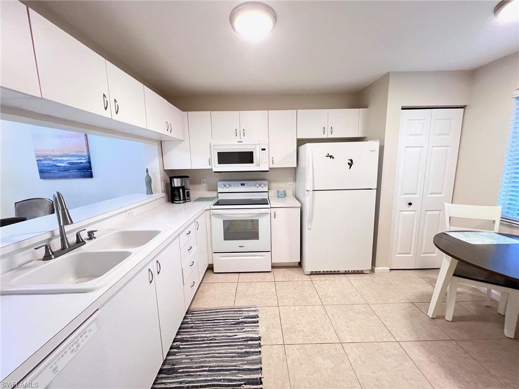1051 Eastham Way, Unit B104 Naples, FL 34104 - Photo 7 of 23 a large white kitchen with cabinets a sink a stove a refrigerator and a window