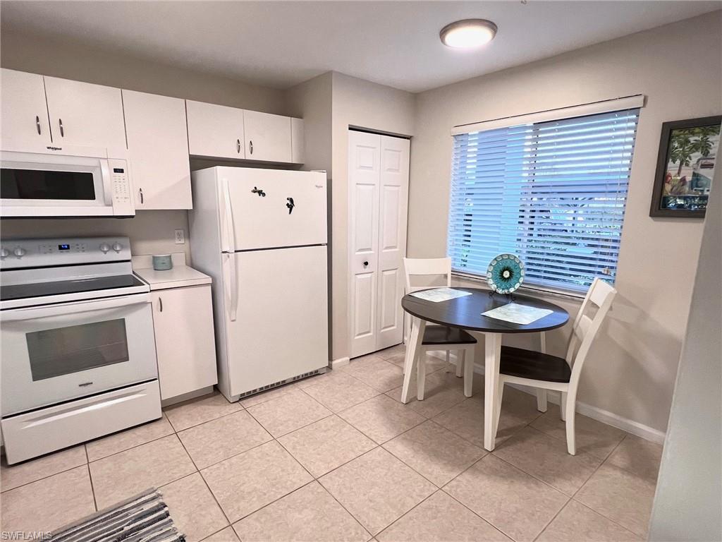 1051 Eastham Way, Unit B104 Naples, FL 34104 - Photo 8 of 23 a kitchen with stainless steel appliances a stove a refrigerator a table and chairs
