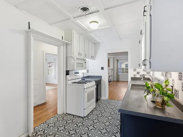 a kitchen with stainless steel appliances kitchen island granite countertop a refrigerator a sink a stove and white cabinets