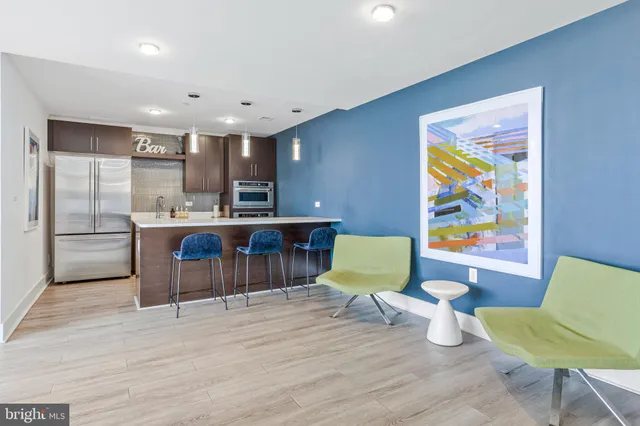 a living room with stainless steel appliances furniture and wooden floor