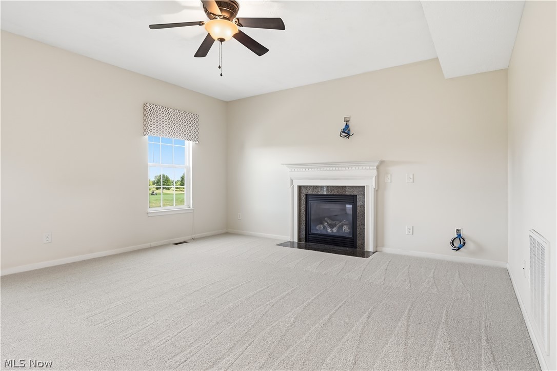 3280 Seven Bridges Road Medina, OH 44256 - Photo 11 of 41 Living area featuring a gas fireplace with a decorative mantel and hearth, vaulted ceiling, ceiling fan with light fixture, light-toned carpeting, and a window with a patterned valance
