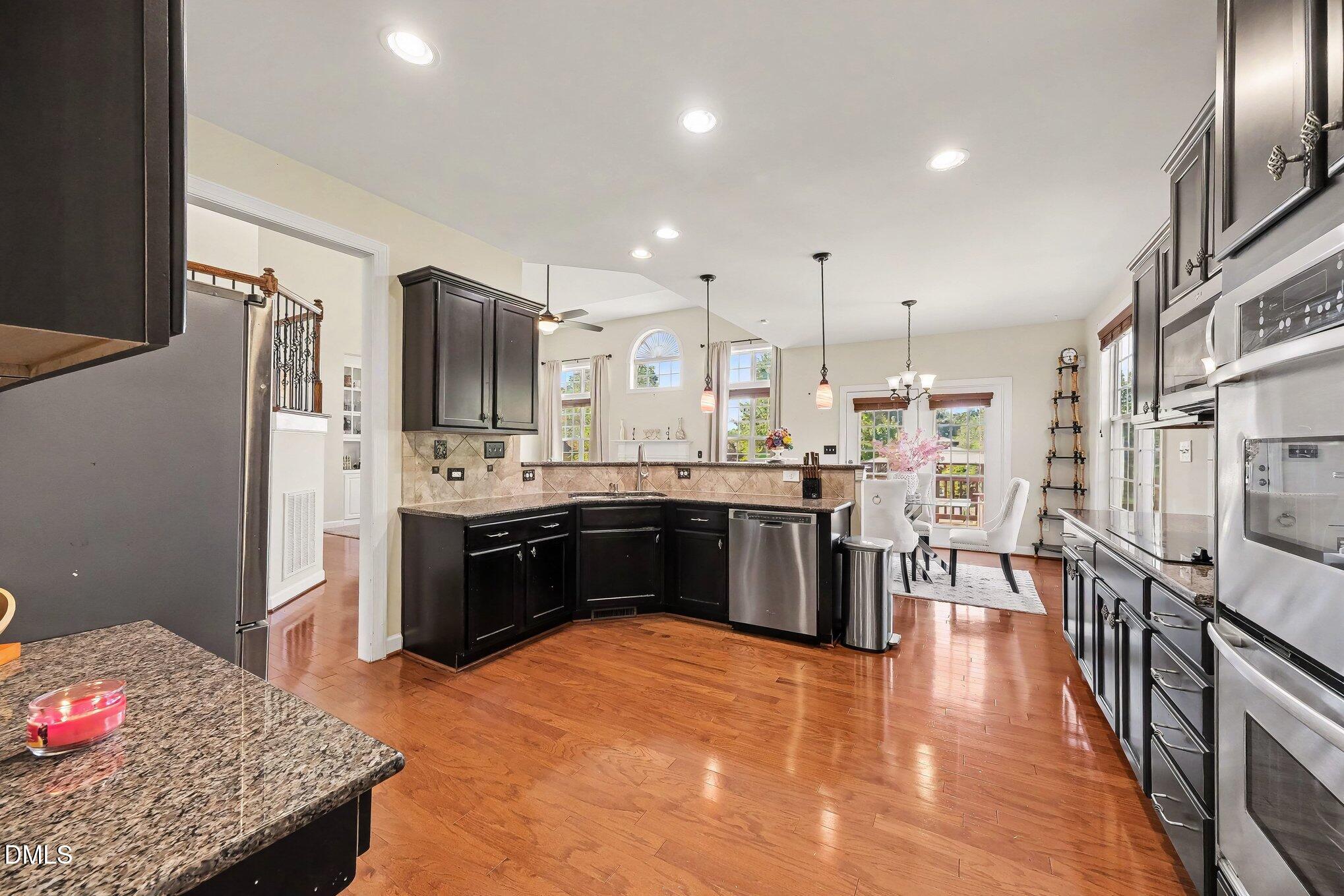 4000 Banks Stone Drive Raleigh, NC 27603 - Photo 18 of 60 a large kitchen with stainless steel appliances kitchen island granite countertop a large kitchen island a sink dishwasher a refrigerator and wooden floor