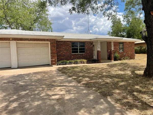 a front view of house with yard and trees in the background