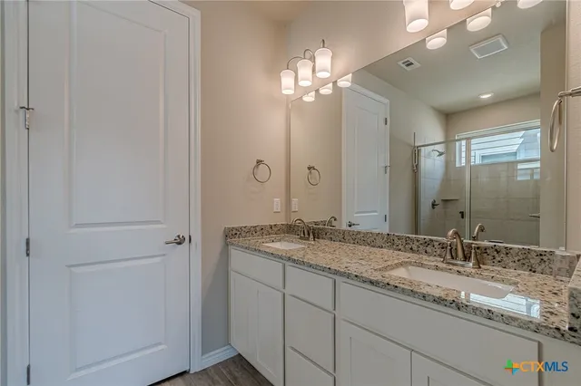 a bathroom with a granite countertop sink a large mirror and a shower